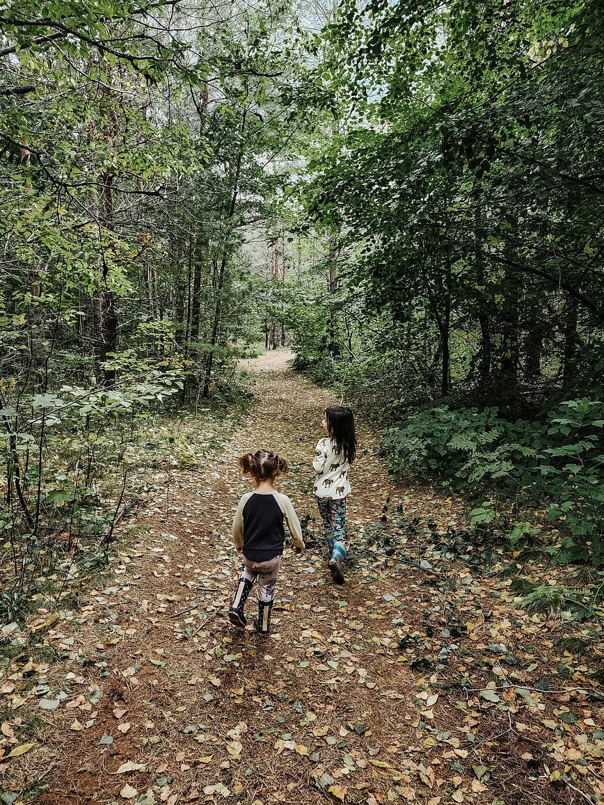 Two children running through a wooded trail