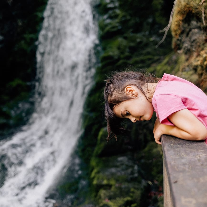Girl looking out over waterfall during a hike